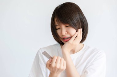 Kadın diş ağrısı nedeniyle elinde ağrı kesici paketiyle yanağını tutuyor..