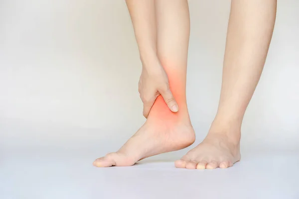事故による足首の怪我により女性の手が彼女の赤い足首に触れる — ストック写真