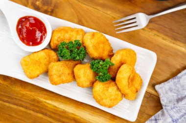 Restoranda beyaz bir tabakta kızarmış tavuk nugget yemek. Üst görünüm.