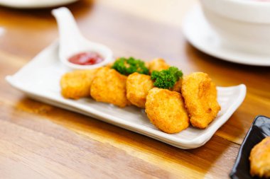 Lokantada beyaz bir tabakta kızarmış tavuk nuggetları. Seçici odak.