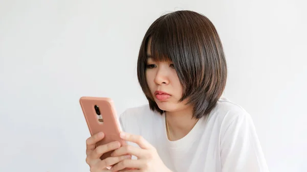 白いシャツの短い髪のアジアの女性は ソーシャルメディアを使用したり オンラインでコミュニケーションするために電話を持っています — ストック写真