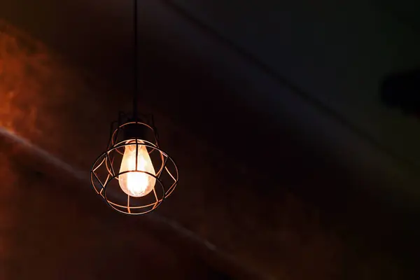 Light bulbs hanging from the vintage ceiling glow a golden yellow. Copy space.
