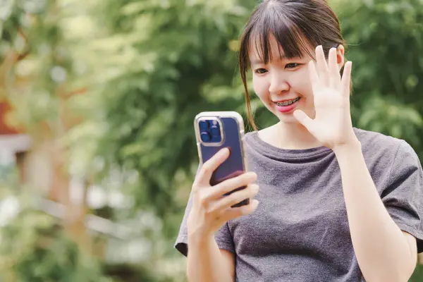 Asian woman is holding a phone to use social media or communicate online with a cheerful face.