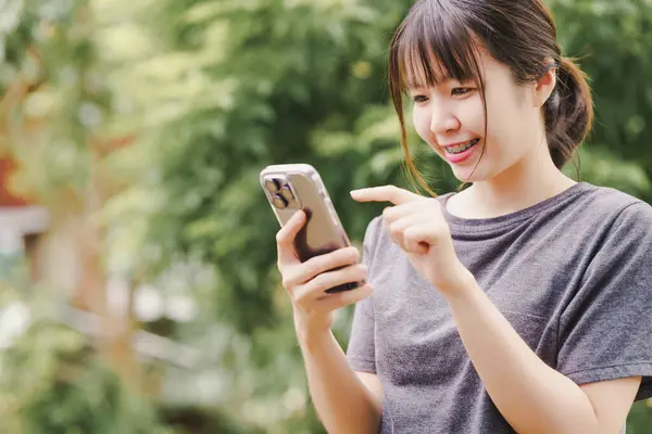 Asian woman is holding a phone to use social media or communicate online with a cheerful face.