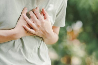 Close-up of women hand held his chest in pain. Concept of heart disease. clipart