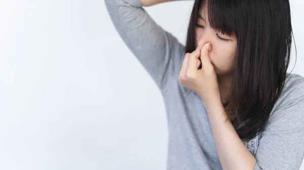Asian woman covers her nose because of the bad smell coming from her armpits.