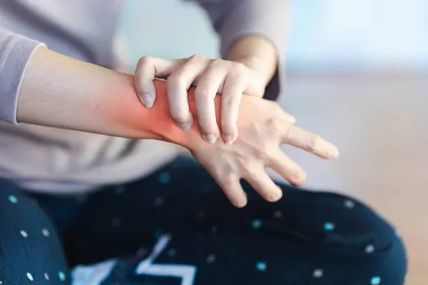 A woman\'s wrist is in pain and a red area is made to show the pain point.