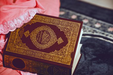 Dua kıyafetleri içinde bir kadının eli Kuran 'ı dua örtüsünde tutuyor..