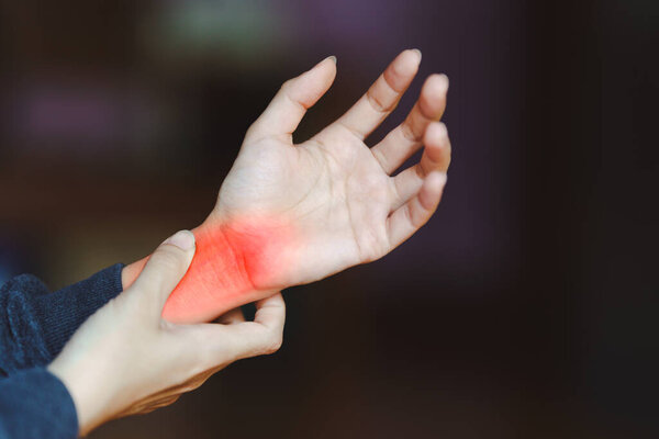 Человек, держащий запястье с красным выделением, указывающим на боль или травму, возможно, запястный туннель или артрит. Концепция проблемы дискомфорта рук и здоровья.