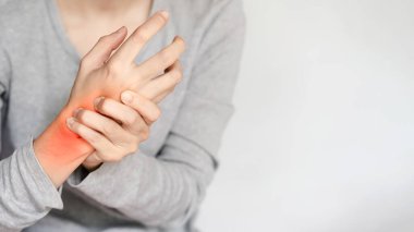 Gri gömlekli birinin kırmızı acı veren bileğini tutarken, yaralandığını ya da rahatsız olduğunu gösteren yakın plan görüntüsü..