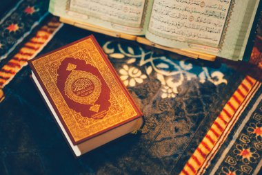 Kuran, İslam 'ın kutsal kitabı, burada bir dua paspasında dinlenirken resmedilmiştir. Kitap, Arapça yazılmış bir sayfayı açıyor..