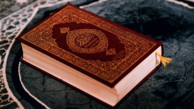 Güzel dekore edilmiş bir Kur 'an' ın yakın plan bir taş yüzeyde dinleniyor, dini kitabın karmaşık tasarımı ve zengin renklerini yakalıyor..