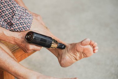 A close-up view of a person using a massage device on their foot, promoting relaxation and self-care. The warm tones and focus highlight well-being and comfort. clipart