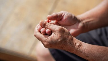 Görüntü ellerin kapanmasını, görünüm dokusunu ve yaşlanmış cildin detaylarını görüntüler, tefekkür ve sükunet hissini iletir.