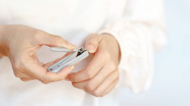 Bir insan tırnaklarını törpülemek için tırnak makası kullanır, kişisel bakım ve hijyenini gösterir..