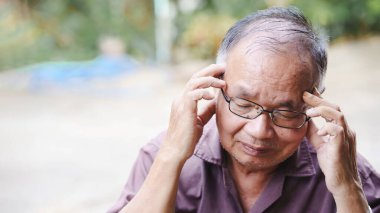 Düşünceli yaşlı bir adam derin düşünceleri ya da duyguları yansıtan şakaklarına dokunur..