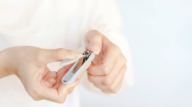 Bir insan tırnaklarını kesmek için tırnak makası kullanıyor, kişisel bakım ve hijyen sergiliyor..