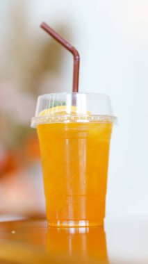 Açık bir fincanda, bir dilim limonla süslenmiş, bulanık bir arka planda serinletici bir portakal suyu..