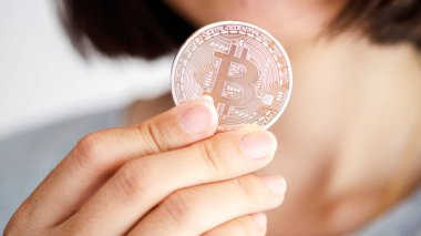 Bir kişi bir Bitcoin tutuyor, kripto para biriminin fiziksel temsilini tasarım ve yeniliğine odaklanarak sergiliyor..