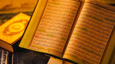 Karmaşık bir yazı ve daha küçük bir kitapla Kuran 'ı aç, sıcak bir zemin üzerine kurulmuş..