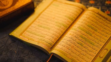 Arapça kaligrafiyi anlatan süslü kumaş üzerine Kur 'an açın. Haşhaş kuralları ve İslami ibadet ve öğrenim için sıcak aydınlatma..