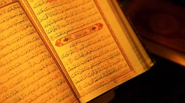 İslam öğretilerini ve hürmetini vurgulayan sıcak aydınlatma altında canlı Arapça yazı ve aydınlatılmış sınırlar içeren Kur 'an sayfalarını aç.