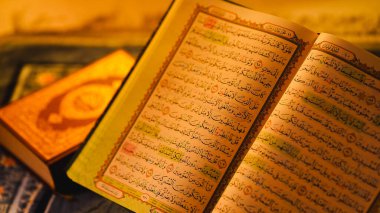 Dini metinler ve sıcak aydınlatmalarla çevrili bir yüzeyde açık Kur 'an.