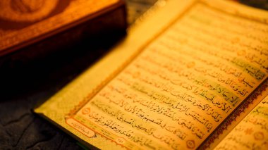 Kuran 'ın Arapça kaligrafi ve taçotu renk kodlarıyla kapatılmış sıcak ortam ışığı İslam ruhaniliğini simgeliyor..