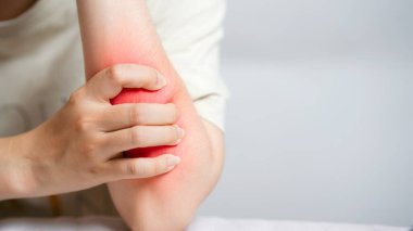 Dirsek ağrısı çeken, iltihaplı bölgeyi tutan bir kadın..