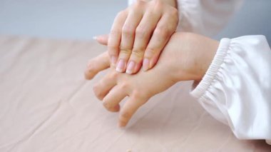 El ve bilek masajı terapisi. Kadın ellerini beyaz kollu gösteriyor. Rahatlatıcı ve sakin bir bakım için.