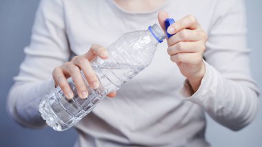 Temiz plastik su şişesi, hidrasyon konsepti, sağlıklı yaşam tarzı, günlük giysiler açan biri.