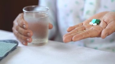 Yaşlı el hapları ve bir bardak su, sağlık hizmetleri ve günlük sağlık yönetimi rutini için ilaçlar