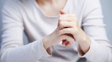 Eklem basınç gerilimi ya da ağrı yönetimini göstermek için iki elini bilek bölgesinde kenetlemek.