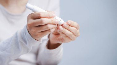 Bir kişi kan şekeri testi diyabetini kontrol etmek için kan glikozu ölçerini kullanarak kapatır.