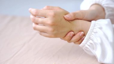 El ve cilt hassasiyetinde yumuşak doğal ışık ve yaralanma gösteren acı içinde bileğini tutan kişi.