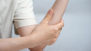 Kol ve dirseği tutan kişi nazikçe cilt bakımını ve desteğini göstermektedir.