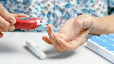 Şeker seviyesini ölçmek için kan şekeri ölçer kullanan yaşlı bir kişi, evde diyabet yönetimi, ellerin kapatılması, sağlık ve tıbbi konsept