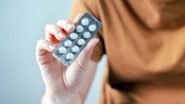 Su toplayan beyaz tablet el, kahverengi gömlekli, sağlık sigortası ilaçlı tıbbi tedavi konseptini kapatıyor.