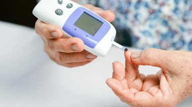 Kan şekeri ölçer diyabet testi. Yaşlı el, kan şekerini ölçüyor. Sağlık hizmetleri tıbbi cihaz parmak deliklerini izliyor..