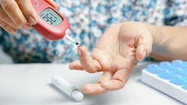 Kan şekeri ölçer diyabet testi. Parmak iğnesi. Yaşlı el aleti. Yaşlı bir kişi kan şekeri seviyesini ölçer ve kendini gösterir..