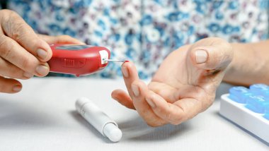 Evde kan şekeri seviyesini, diyabet yönetimini, sağlık hizmetlerini ve kendini izleme kavramını kontrol etmek için kan şekeri ölçer kullanan yaşlı kişi.