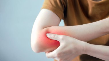 Dirsek ağrısı çeken, kırmızı iltihaplı bölgeyi gösteren, eklem ağrısı, yaralanma veya artrit konsepti, kol ve el kapama, sağlık ve tıbbi sorun gösteren bir kişi.