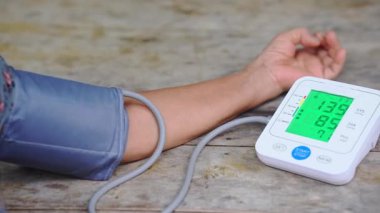 Kolunda kelepçe ve yeşil ekran ekranı olan dijital tansiyon monitörü kullanan bir kişinin yakın çekimi, sağlık, sağlık ve kalp sağlığı içeriği için uygundur..