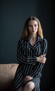 Genç, güzel esmer, siyah çizgili elbiseli, odada poz veren.