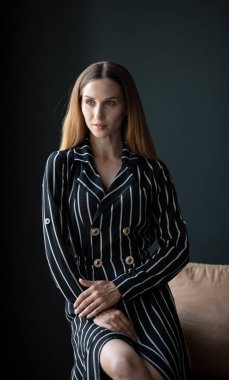 Genç, güzel esmer, siyah çizgili elbiseli, odada poz veren.