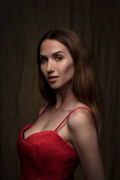 Hermosa Joven Morena Posando Vestido Rojo Sobre Fondo Marrón Oscuro —  Fotos de Stock