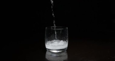 Koyu arkaplanda buzla bardağa alkol dökmek.