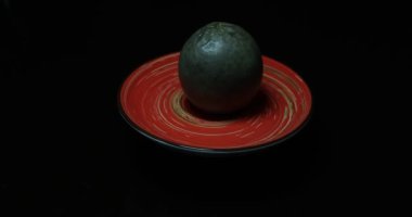 Siyah arka planda siyah bir kasede kırmızı ve yeşil yumurta..