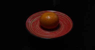 Siyah bir kasede siyah bir arka planda portakal meyvesi