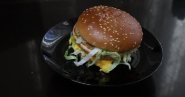 Peynirli burger, domates, marul ve soğanlı siyah arka plan.